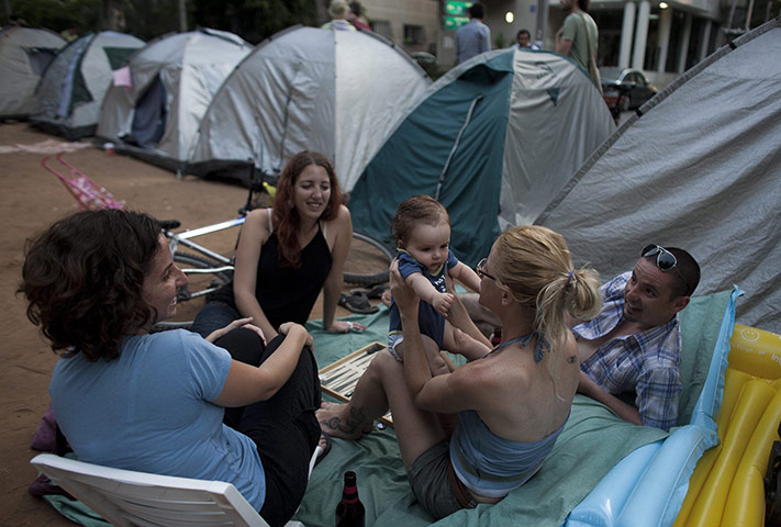Tent City: A young mother plays with her child while sitting with other Israelis 