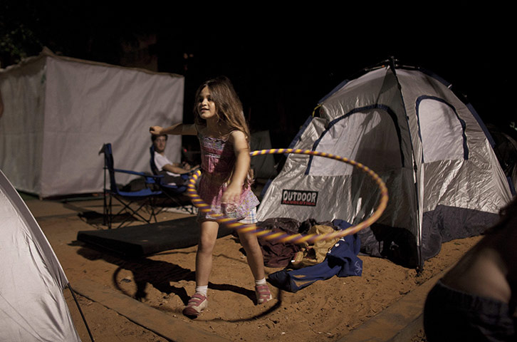 Tent City: A girl plays hula hoop outside her tent