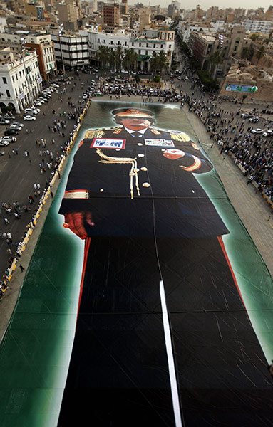 24 Hours: Muammar Gaddafi supporters gather round a massive portrait of him in Libya