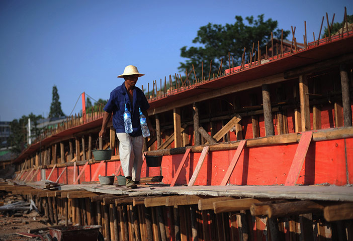 24 hours: Wuhan, China: A worker carries water at the Gate of Wuchang Uprising