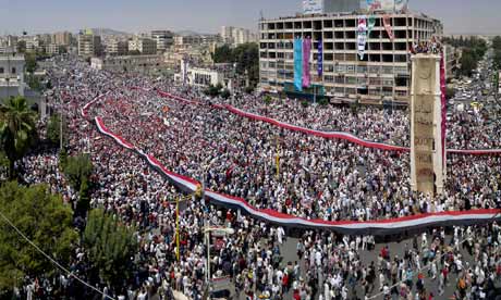Syrian protesters carry a giant national flag during a rally in al-Assy square, Hama, Syria