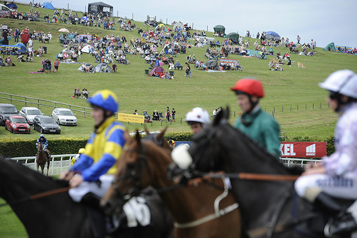 Glorious Goodwood Wed: Punters watch for free on the hill overlooking the course 