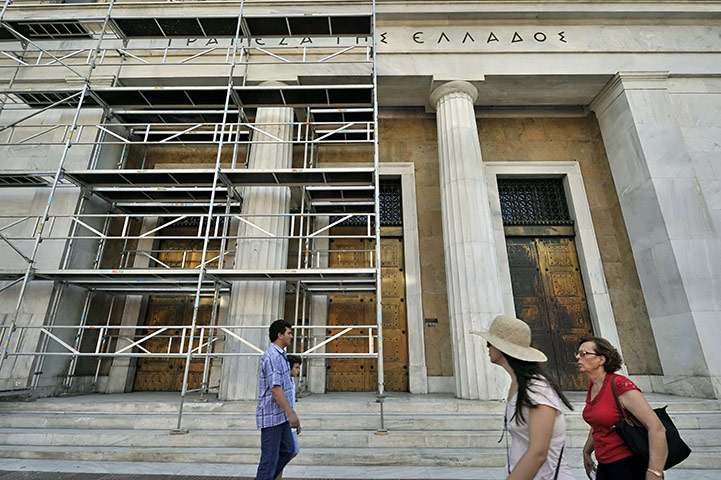 Week in Business: People walk past the Bank of Greece with scaffolding in Athens 