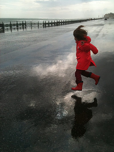 Jump: A girl in a red coat jumps in puddles in Brighton by Dr Claudio Alonso