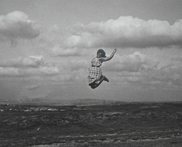 Jump: Woman jumping on the brow of a hill by Roger Adkins