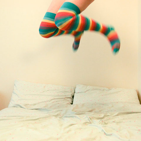 Jump: girl with stripey socks jumping on a bed