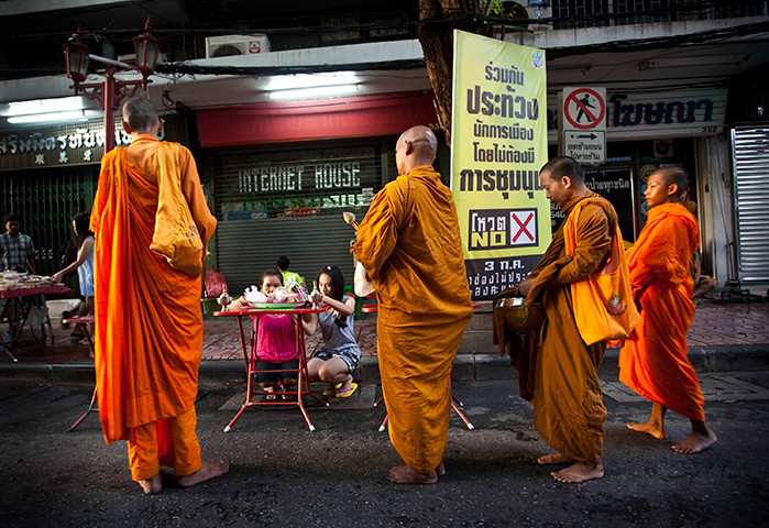 Thailand elections: Buddhist monks gather near an election poster for Pheu Fah Din Party
