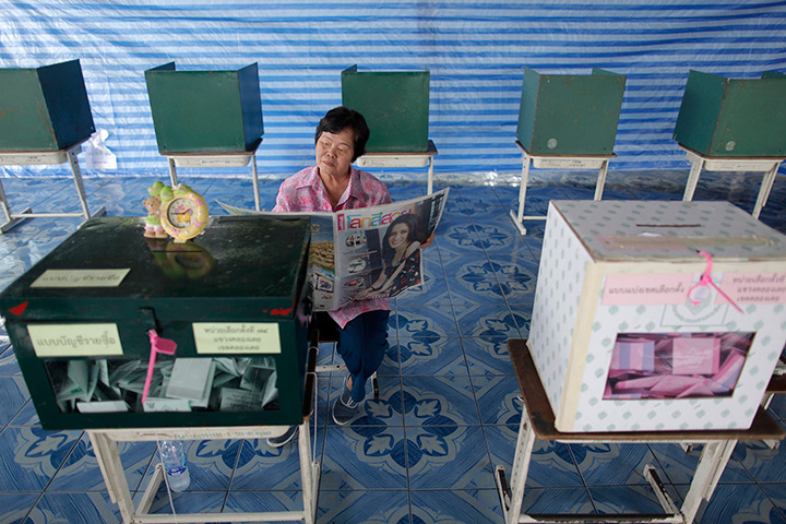 Thailand elections: An election official reads newspapers at a polling station in Bangkok