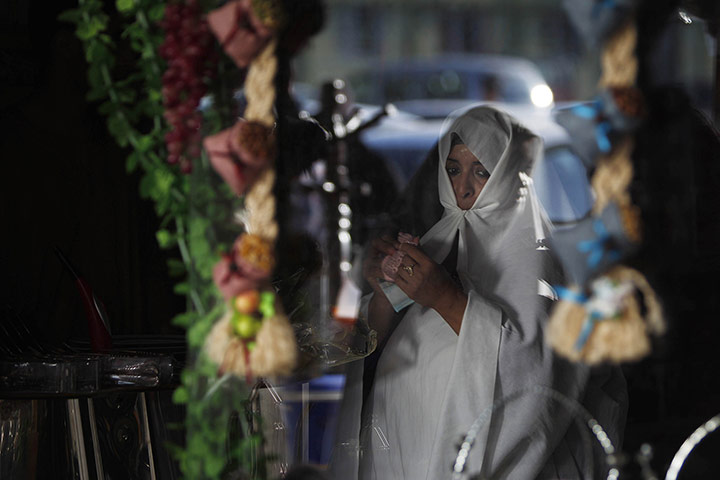 24 Hours: A Libyan woman is seen through a store window as she shops at a market