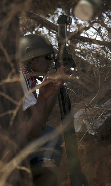 24 Hours: A rebel fighter monitors the movement of pro-Gaddafi soldiers