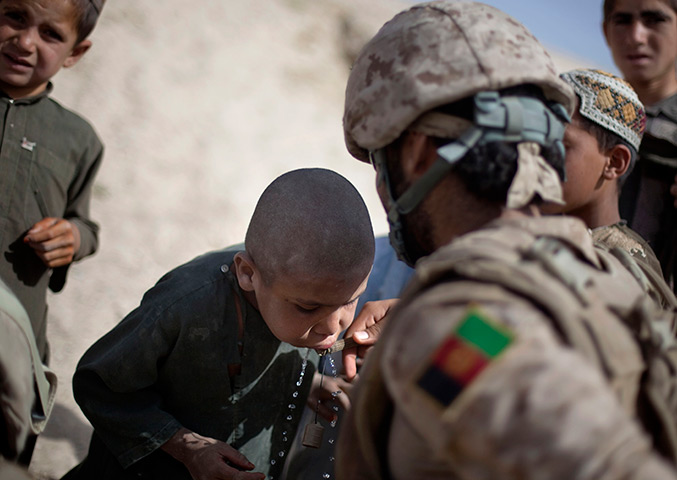 24 hours in pictures: An Afghan boy takes a drink of water from a US medic