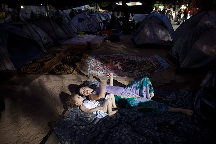 24 hours in pictures: A young mother plays with her son amid tents in the tent city in Tel Aviv