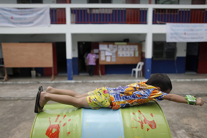 24 hours: Bangkok, Thailand: A child plays in front of a polling station 