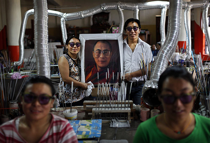 24 hours: Dharmsala, India: Tibetan glass makers hold a portrait of the Dalai Lama