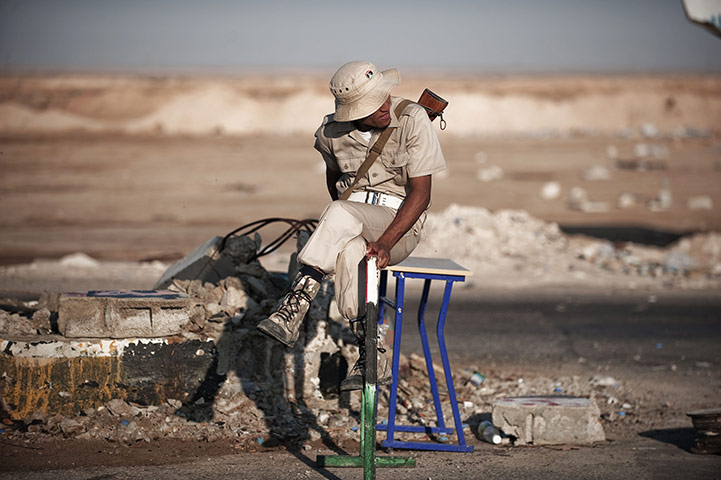24 hours in pictures: A Libyan rebel fighters waits at the Ajdabiya Western checkpoint