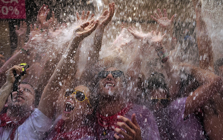 Pamplona revellers: Revellers react as water is thrown from a balcony during the Chupinazo