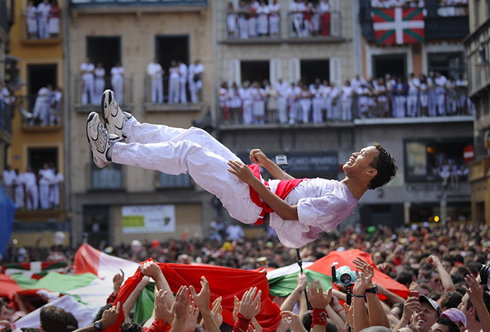 Pamplona revellers: A man is tossed into the air during the Chupinazo
