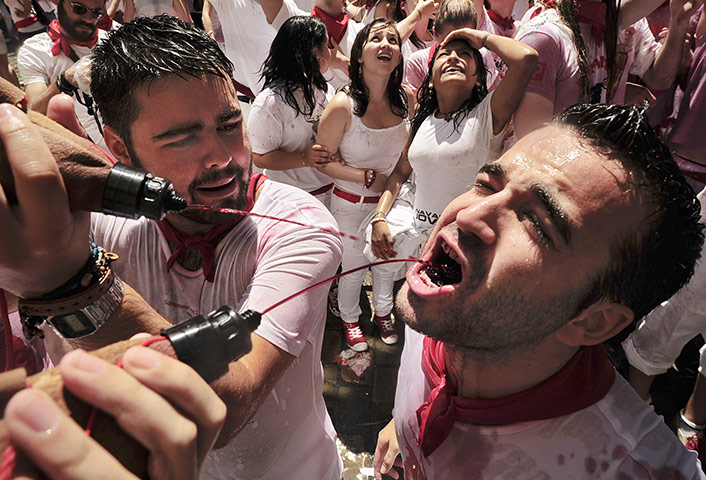 Pamplona revellers: Revellers drink wine from a small wineskin, in Pamplona, Spain
