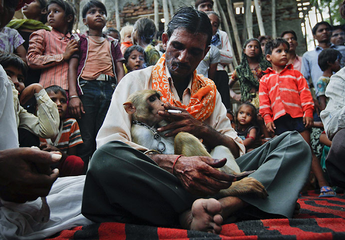 24 Hours in Pictures: Rajesh, a rickshaw driver, shares a cigarette with his monkey in India