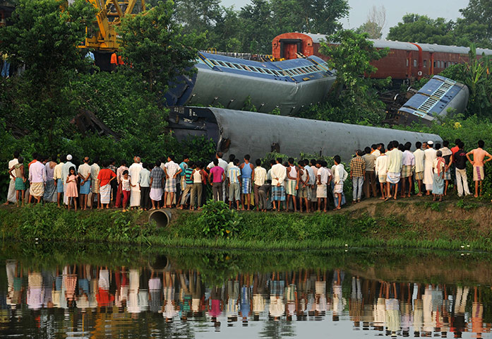 24 hours: Bagharpur, India: Bystanders watch rescue workers at a train crash