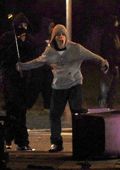 UK Riots: A rioter with a golf club challenges police officers in Liverpool