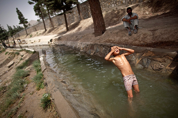 24 hours in pictures: An Afghan boy throws himself backwards to a stream of water