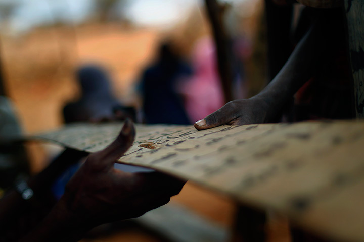 24 hours in pictures: Somali refugees share a prayer tablet at an outdoor madrasa