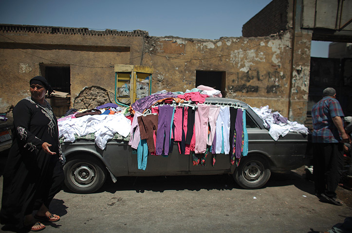 24 hours in pictures: An Egyptian woman passes by a car with clothes laid out for sale