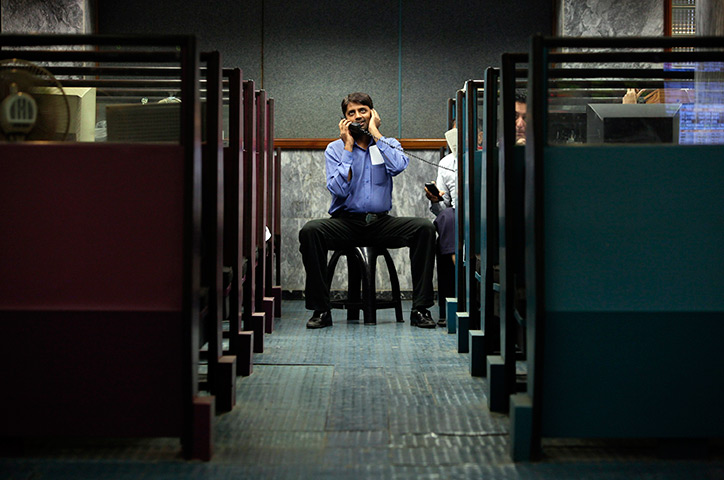 24 hours in pictures: A man uses a phone between booths, Karachi Stock Exchange
