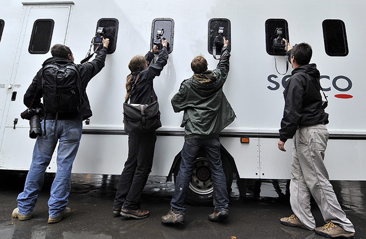 London riots aftermath: Photographers take pictures of a prison van as it leaves court in London