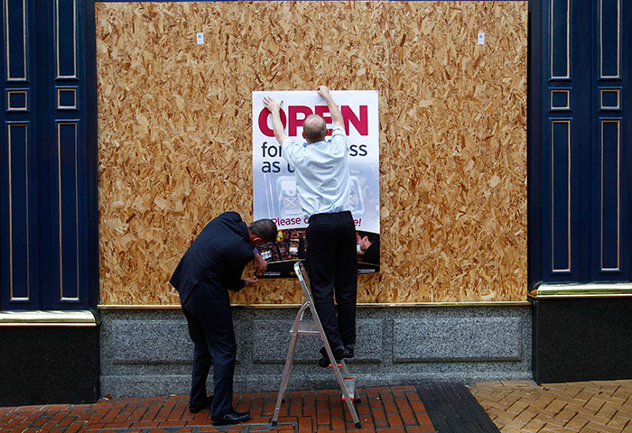 London riots aftermath: Workers attach an 'Open for Business' sign to boards on a shop, Birmingham