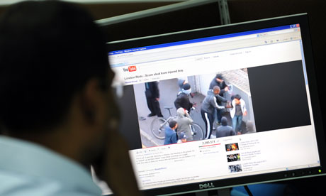 A man watches video images of the rioting on YouTube