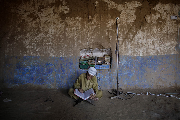 24 hours in pictures: A Pakistani youth reads from the Qur'an in a Mosque