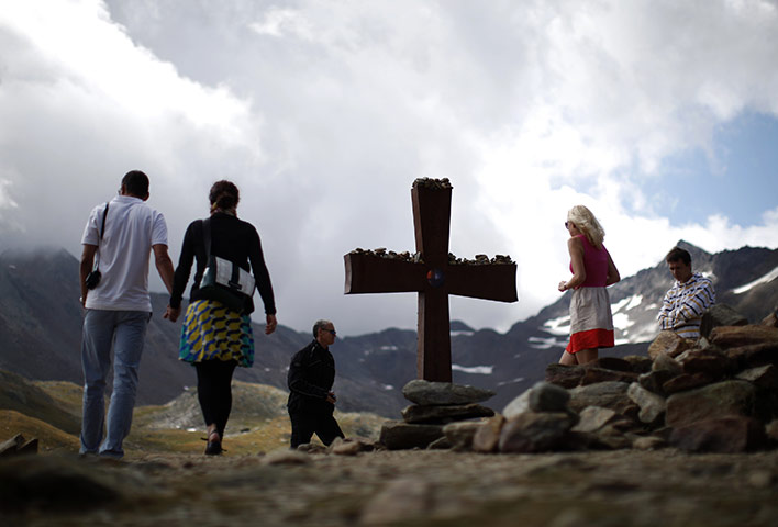 24 hours in pictures: Austria: Tourists walk next to the cross on the Timmelsjoch mountain