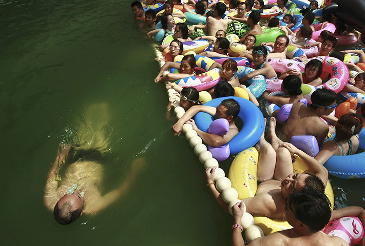 24 hours in pictures: Daying, China: Holidaymakers watch a man swimming past them