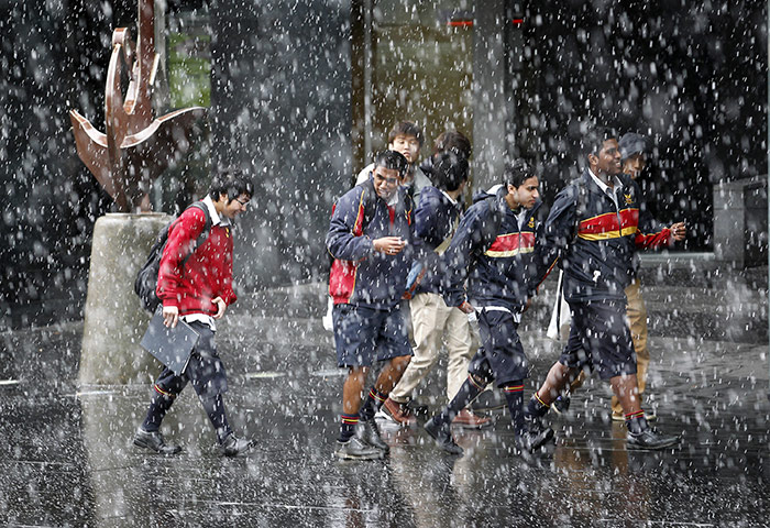 24 hours in pictures: Auckland, New Zealand: People walk through a snow shower
