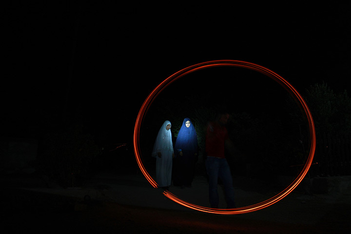 24 hours in pictures: Muslim woman stand around Palestinian man plays with fireworks,