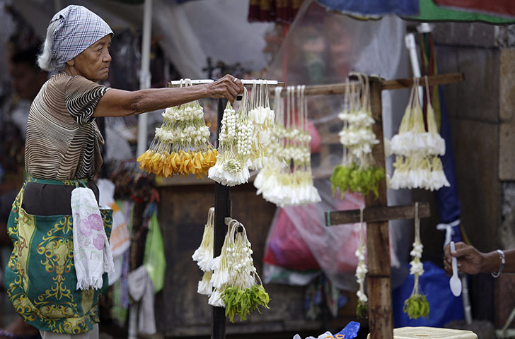 24 hours in pictures: : Manila, Philippines: A Filipino woman vendor arranges Sampaguita garlands 