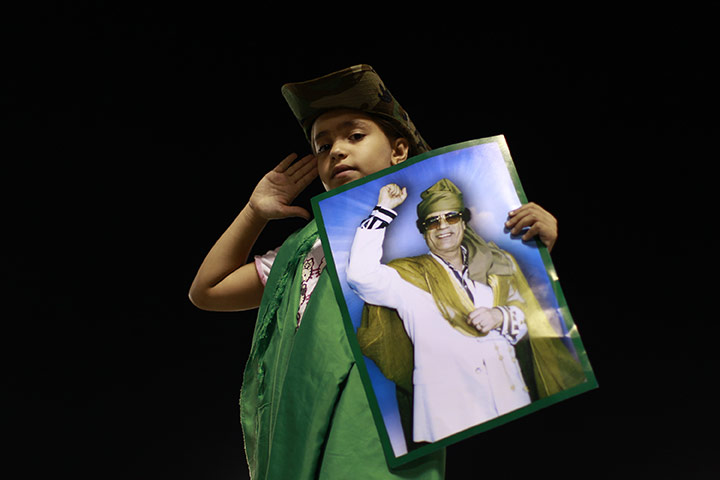 24 hours in pictures: Tripoli, Libya: A child salutes as she holds up a poster of Moammar Gaddafi