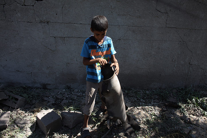 Israeli air strikes: A Palestinian boy holds the remains of an Israeli missile outside his home