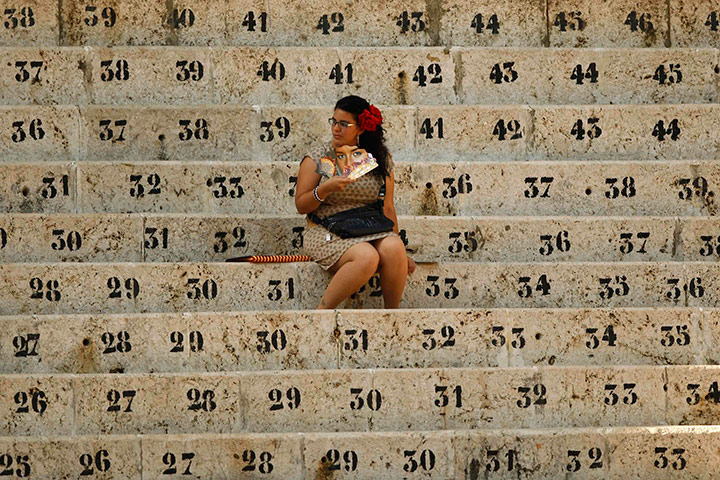 24 hours in pictures: A woman fans herself as she waits for the start of a bullfight