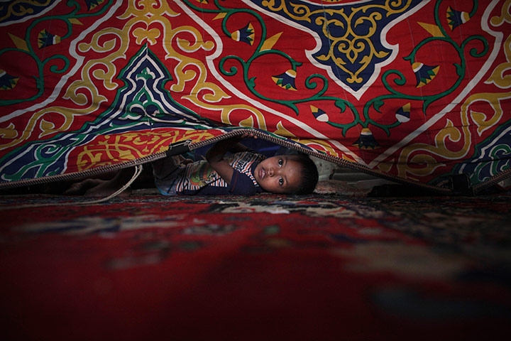 24 hours in pictures: An Egyptian boy peaks out from beneath  a curtain
