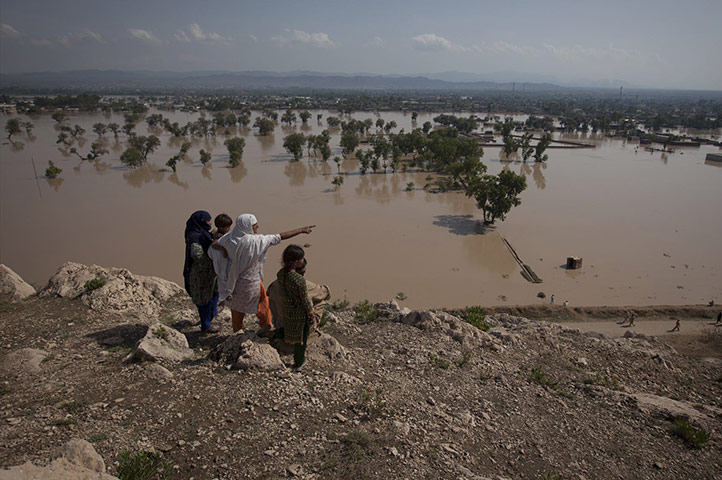 FTA: Adrees Latif   : A family points towards partially submerged houses 