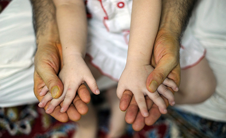 24 hours in pictures: Kuala Lumpur, Malaysia: An Afghan migrant holds the hands of his daughter