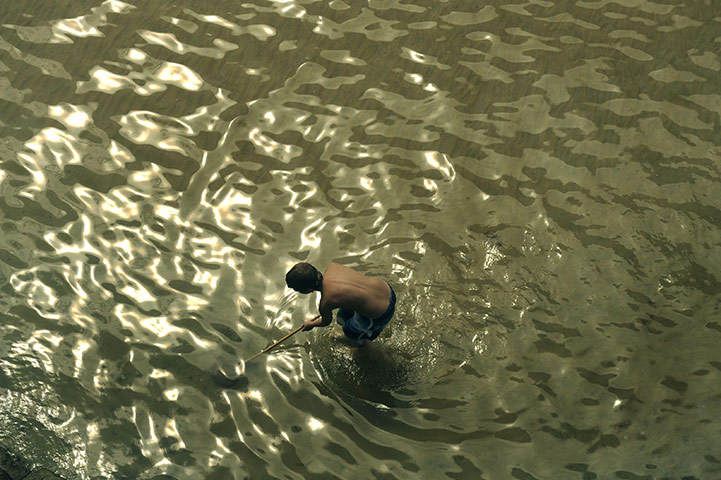 24 hours in pictures: San Sebastian, Spain: A boy tries to catch a fish at La Concha beach 