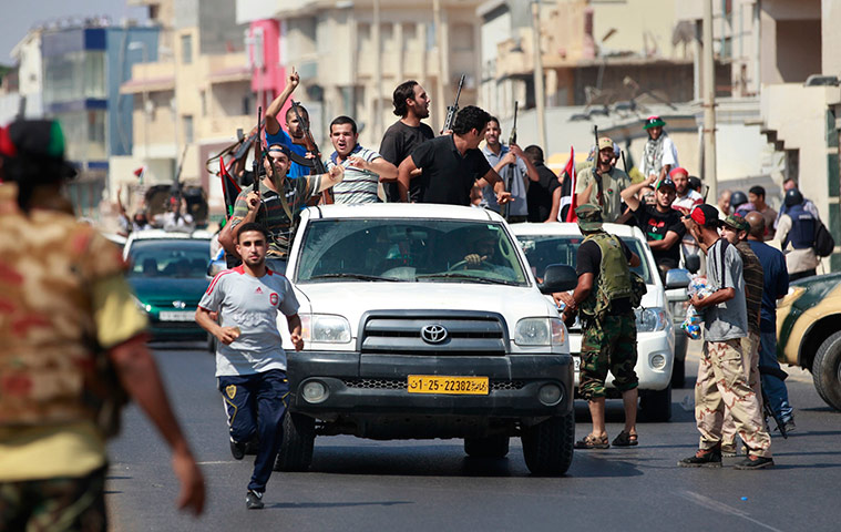 Muammar Gaddafi Libya : Libyan rebel fighters celebrate as they drive through Qarqarsh district
