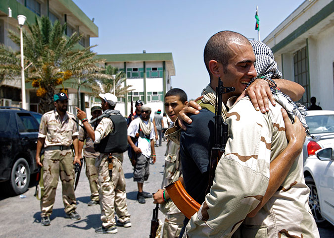 Libya update: Libyan rebel fighters embrace at the former female military base in Tripoli