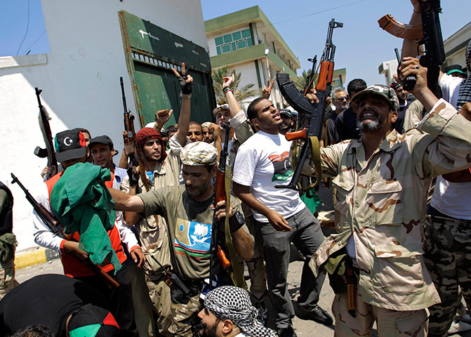 Libya update: Libyan rebel fighters gesture at the former female military base in Tripoli
