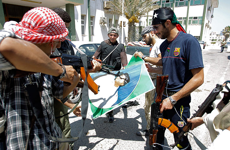 Libya update: Libyan rebel fighters deface a portrait of Muammar Gaddafi in Tripoli