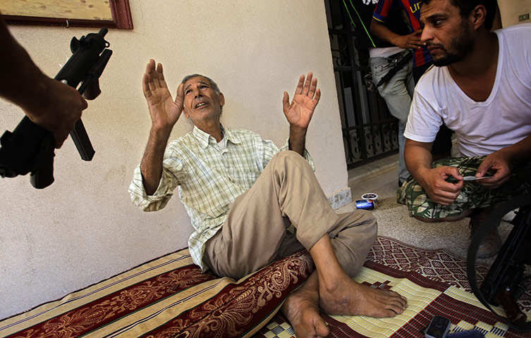 Battle for Tripoli: Rebel fighters with a suspected pro-Gaddafi soldier after he was captured